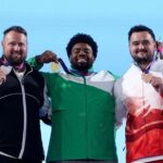Gold medalist Chukwuebuka Enekwechi of Team Nigeria in green and white tracksuit stands between silver medalist Tom Walsh of New Zealand in black and white and bronze medalist Scott Lincoln of England in red and white as all three hold up their medals on the podium during the Mens Shot Put Final medal ceremony on Day 7 of the Glasgow 2026 Commonwealth Games at Scotstoun Stadium July 30 2026  trybalnews