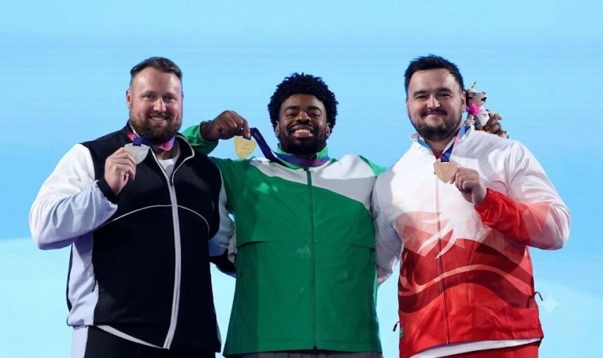 Gold medalist Chukwuebuka Enekwechi of Team Nigeria in green and white tracksuit stands between silver medalist Tom Walsh of New Zealand in black and white and bronze medalist Scott Lincoln of England in red and white as all three hold up their medals on the podium during the Mens Shot Put Final medal ceremony on Day 7 of the Glasgow 2026 Commonwealth Games at Scotstoun Stadium July 30 2026  trybalnews