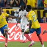 Jhon Arias of Colombia wearing a yellow jersey with number 11 and blue shorts celebrates with a wide smile and outstretched arm after scoring his teams first goal He is joined by teammate Davinson Sanchez defender 23 also in a yellow jersey and blue shorts running toward him on the pitch Another Colombian player in yellow is visible to the right In the background a Ghana player in a white kit walks away with Colombian fans in yellow shirts and a red Coca Cola advertising board behind them The scene is from the 2026 World Cup Round of 32 match between Colombia and Ghana at Kansas City Stadium on July 3 2026  trybalnews