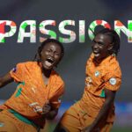 Two soccer players in orange uniforms celebrate on the field as PASSION appears in colorful letters above them on the graphic background  trybalnews