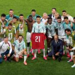 Portugals Cristiano Ronaldo wearing a light blue and white number 7 jersey stands center holding up a red Portugal jersey with the number 21 to commemorate late teammate Diogo Jota He is surrounded by smiling teammates and coaching staff in matching kits and training bibs posing together on a green pitch after their 2 1 FIFA World Cup 2026 Round of 32 win over Croatia in Toronto  trybalnews