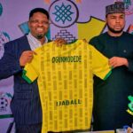 New Kano Pillars Technical Adviser Daniel Ogunmodede and Kano Pillars Chairman Alhaji Ahmad Musbahu Garo holding up a yellow and green Kano Pillars jersey with OGUNMODEDE and IJABALL on the back during his official press unveiling Photo Credit Kano Pillars Media  trybalnews