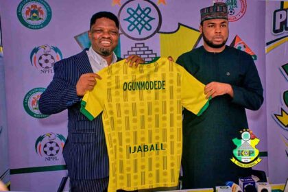 New Kano Pillars Technical Adviser Daniel Ogunmodede and Kano Pillars Chairman Alhaji Ahmad Musbahu Garo holding up a yellow and green Kano Pillars jersey with "OGUNMODEDE" and "IJABALL" on the back during his official press unveiling. Photo Credit: Kano Pillars Media