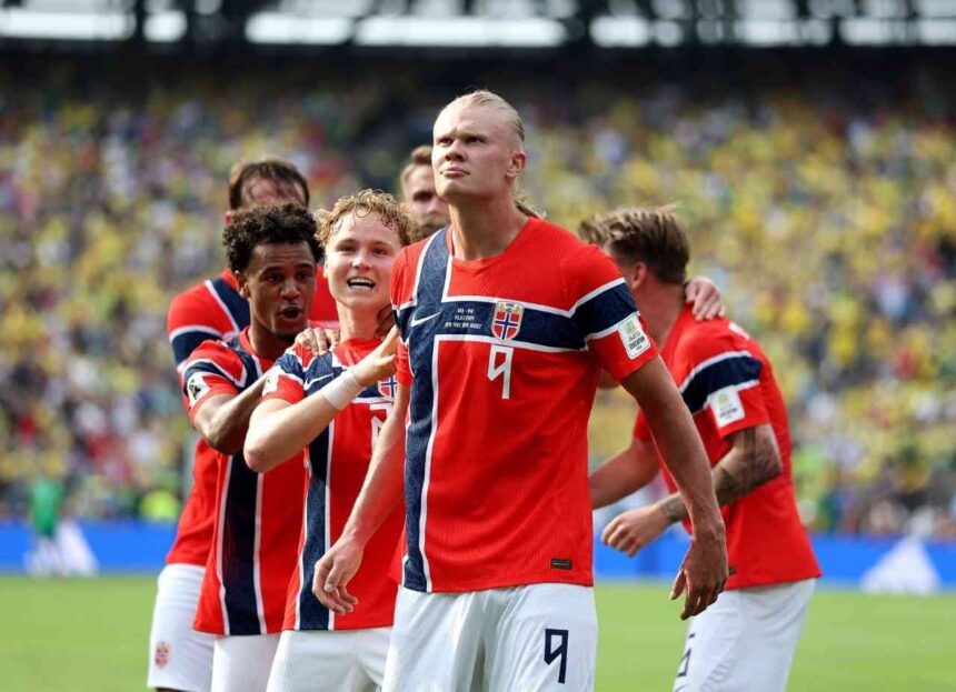 Norway striker Erling Haaland wearing jersey number 9 celebrates with teammates after scoring his teams first goal The players are grouped together on the pitch at New York New Jersey Stadium during the FIFA World Cup 2026 Round of 16 match between Brazil and Norway on July 5 2026 Stadium crowd and green turf are visible in the background  trybalnews