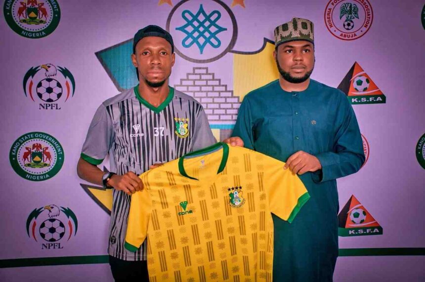 Two men stand side by side holding a yellow Nigeria national team jersey with green trim and crest against a backdrop of football association logos  trybalnews