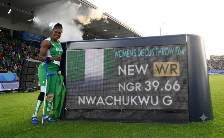 Gold medalist Goodness Nwachukwu of Team Nigeria in green and white kit stands next to a Longines scoreboard at Scotstoun Stadium holding a Nigerian flag and crutches after setting a new world record of 3966m in the Womens Discus Throw F42 44F61 64 Final on Day 6 of the Glasgow 2026 Commonwealth Games July 29 2026  trybalnews