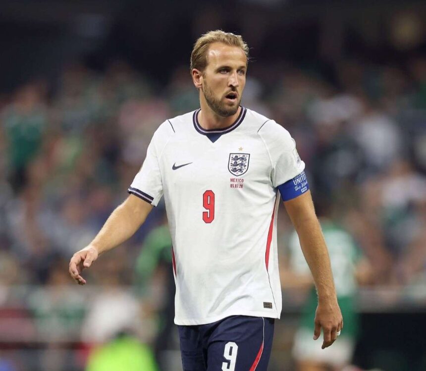England captain Harry Kane wearing jersey number 9 and a white England kit with navy shorts walks on the pitch during play He wears a blue captains armband and looks ahead with a focused expression during the FIFA World Cup 2026 Round of 16 match between Mexico and England at Mexico City Stadium on July 5 2026 Blurred crowd and players in green are visible in the background  trybalnews