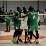 Indoor team sport scene with players in green and white uniforms gathering in a huddle near the net celebrating or encouraging each other on a court  trybalnews