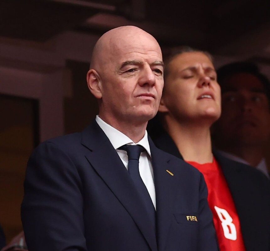 Bald man in a dark suit and tie with a FIFA pin looking ahead at a formal event  trybalnews
