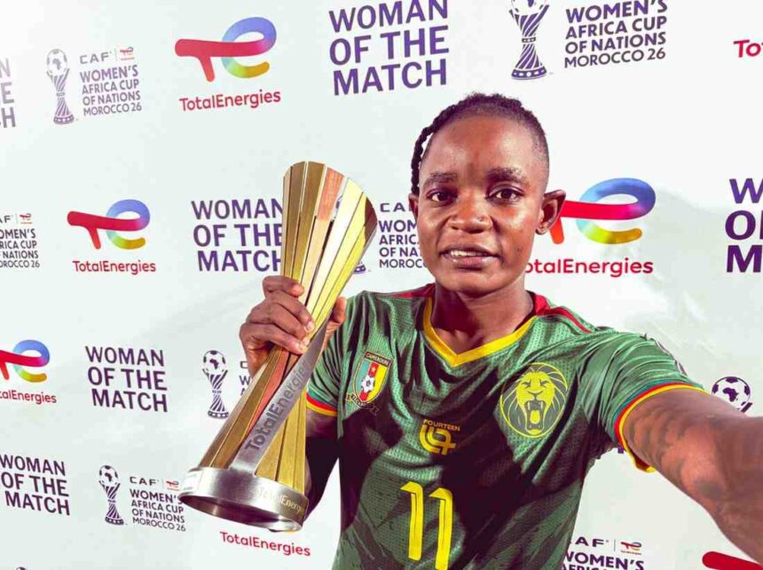Young woman soccer player in a green Cameroon jersey holds a tall gold trophy at a Women of the Match event  trybalnews