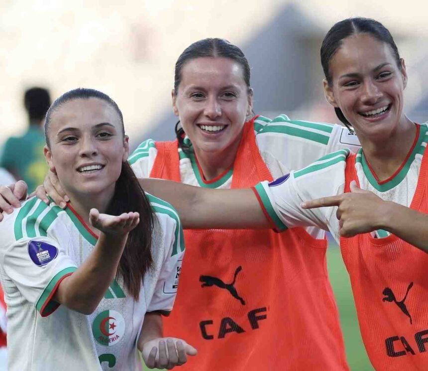 Three female soccer players celebrate together on the field arms around each other and smiling wearing white and green jerseys with orange bibs  trybalnews