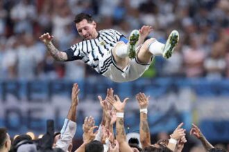 Lionel Messi, wearing Argentina's blue and white striped #10 jersey, is lifted into the air by teammates after Argentina's 3-2 victory over Egypt in the FIFA World Cup 2026 Round of 16 at Atlanta Stadium in Atlanta, Georgia on July 7, 2026. Messi smiles with arms outstretched as multiple hands reach up to celebrate with him in front of a blurred stadium crowd.