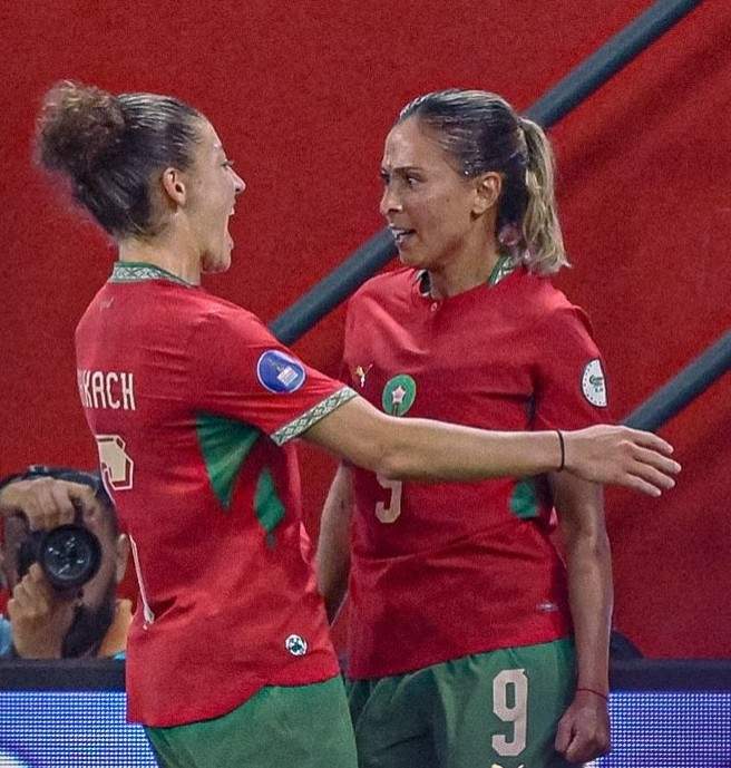 Two female soccer players in red and green uniforms hug and celebrate on the pitch  trybalnews