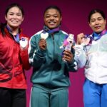 Gold medalist Rafiatu Folashade Lawal of Team Nigeria stands center in green with silver medalist Ann Sophie Taschereau of Team Canada in red on left and bronze medalist Bindyarani Devi Sorokhaibam of Team India in white and blue on right holding medals and mascots on the podium during the Womens 58kg Weightlifting medal ceremony at the Glasgow 2026 Commonwealth Games at SEC Armadillo on July 27 2026  trybalnews