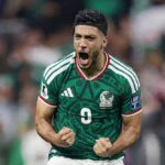 Mexico striker Raul Jimenez wearing a green 9 jersey with white Adidas stripes white shorts and a black headband celebrates with a fierce expression He roars with his mouth open and both fists clenched in front of his chest after scoring Mexicos second goal His Mexico crest and World Cup 2026 sleeve patches are visible The background shows a blurred stadium crowd in green and white This is during the FIFA World Cup 2026 Round of 32 match between Mexico and Ecuador on June 30 2026 at Mexico City Stadium Mexico City Mexico  trybalnews