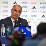 Roberto Martinez head coach of Portugal sits at a press conference table after the FIFA World Cup 2026 Round of 16 match against Spain at Dallas Stadium in Arlington Texas on July 6 2026 He wears a dark suit and tie in front of a sponsor backdrop with a microphone water bottles and a World Cup laptop in front of him  trybalnews