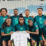Nigerian womens soccer team in teal uniforms posing for a group photo on the field holding a white shirt with a get well message   trybalnews