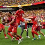 Ruben Vargas 17 of Switzerland celebrates with teammates after scoring the winning fifth penalty in a shootout during the FIFA World Cup 2026 Round of 16 match between Switzerland and Colombia at BC Place in Vancouver British Columbia Canada on July 7 2026 Swiss players in red kits run and jump together on the pitch in front of a packed stadium  trybalnews