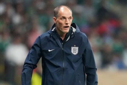 England head coach Thomas Tuchel stands on the touchline wearing a navy blue England training jacket with the Three Lions crest. He looks focused during the FIFA World Cup Round of 16 match at Mexico City Stadium on Sunday, July 5, 2026. Stadium crowd and green seating are blurred in the background.
