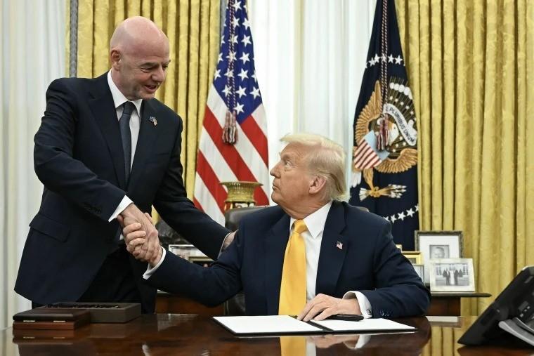 Two men in suits shake hands across a polished desk in the Oval Office with flags and a presidential seal in the background  trybalnews