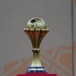Gold trophy with a small globe on top displayed on a pink pedestal  trybalnews