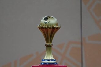 Gold trophy with a small globe on top, displayed on a pink pedestal.