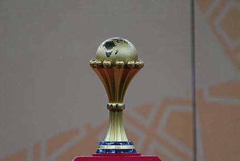 Gold trophy with a small globe on top, displayed on a pink pedestal.