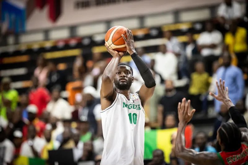 WhatsApp Image 20260703 at 190542 Trybal News Basketball player in a white jersey with green trim and the number 10 takes a jump shot as the crowd watches from the stands behind him trybalnews