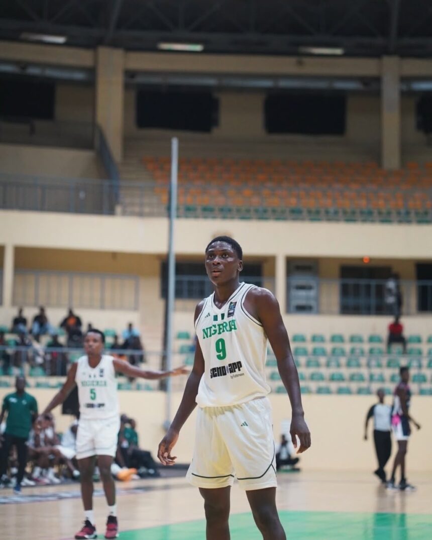 Nigerian basketball player in a white jersey 9 stands on a gym court during a game with spectators and teammates in the background  trybalnews