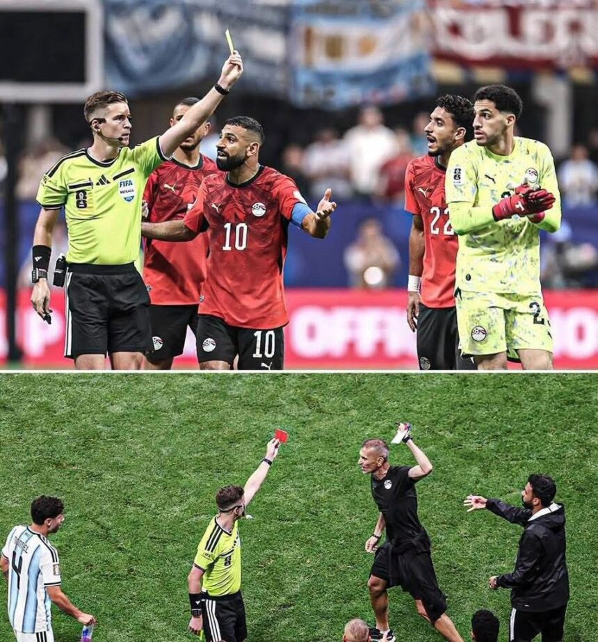 Soccer referee raises a yellow card as a red clad player argues with teammates and a neon clad goalie watches nearby on the field  trybalnews
