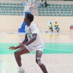 Nigerian basketball player wearing 15 in white uniform dribbling on an indoor court with a camouflage knee brace  trybalnews