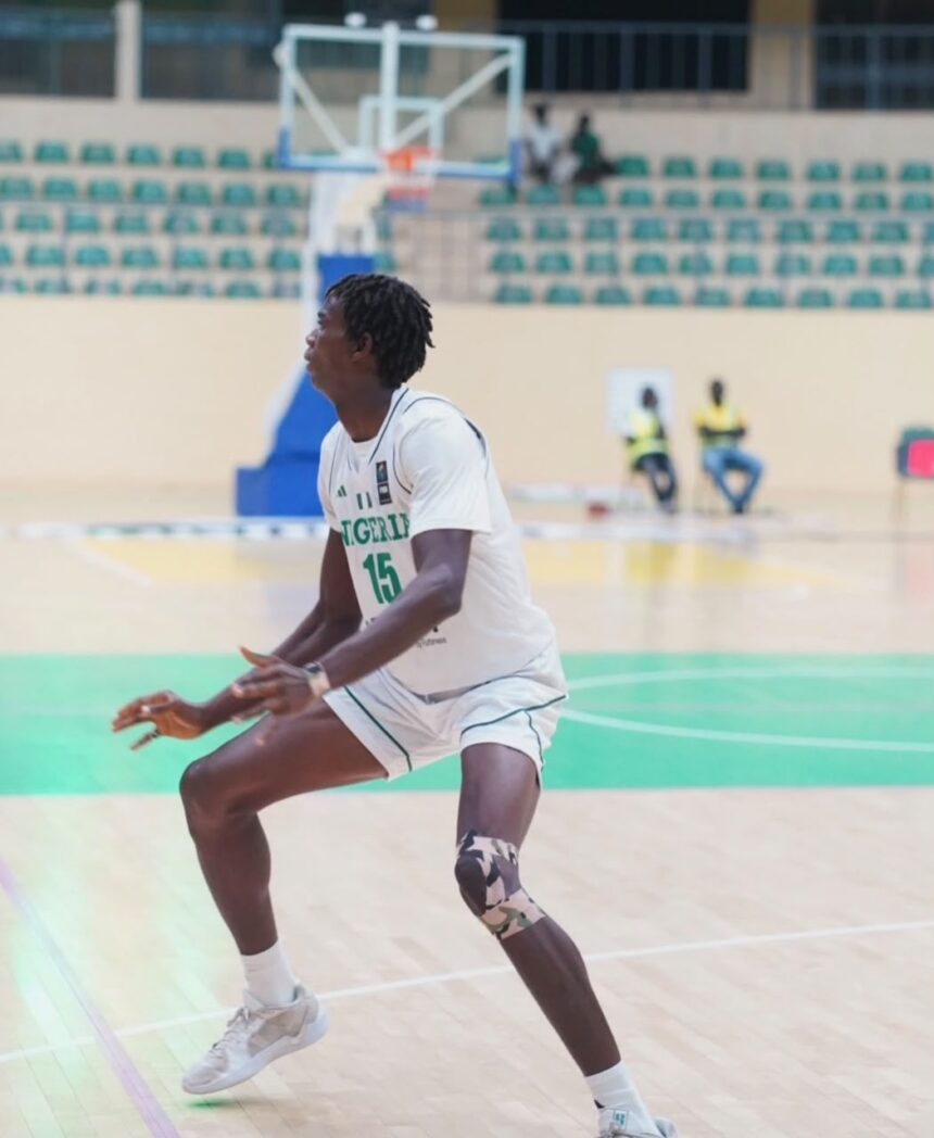 Nigerian basketball player wearing 15 in white uniform dribbling on an indoor court with a camouflage knee brace  trybalnews