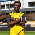 Soccer player in a yellow and black jersey crossing arms in a stadium looking at camera with a smile  trybalnews