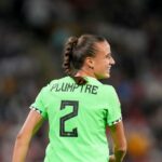 Female soccer player seen from behind in a bright green kit with PLUMPTRE and number 2 smiling on the field  trybalnews