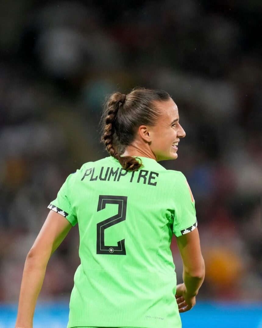 Female soccer player seen from behind in a bright green kit with PLUMPTRE and number 2 smiling on the field  trybalnews
