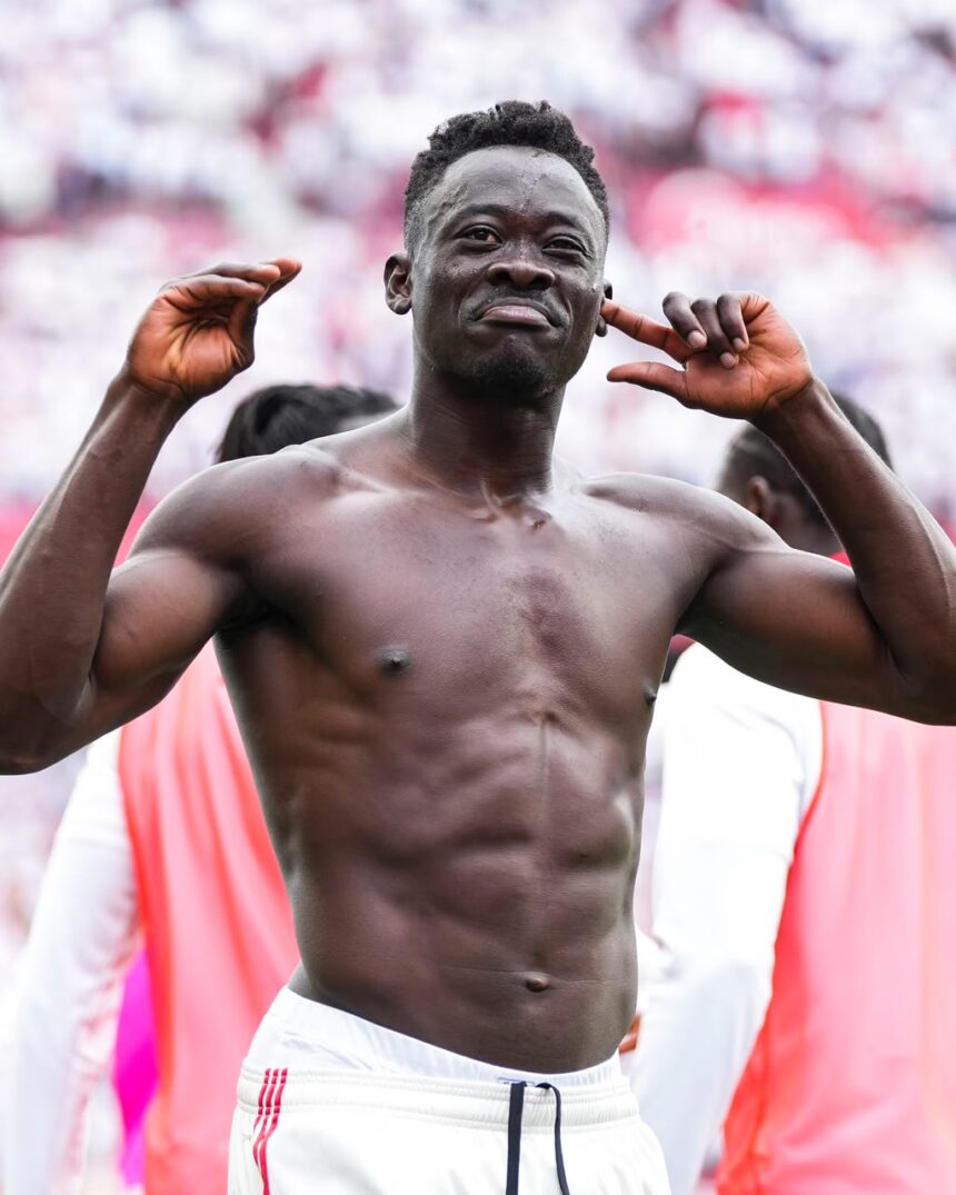 Muscular shirtless man posing with arms raised at a stadium crowd blurred in the background celebrating  trybalnews
