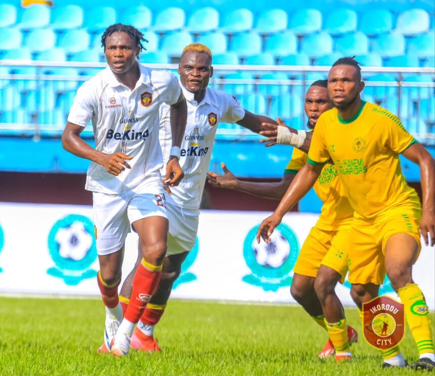 Soccer players in white uniforms chase the ball on a bright green field with blue stadium seats in the background  trybalnews