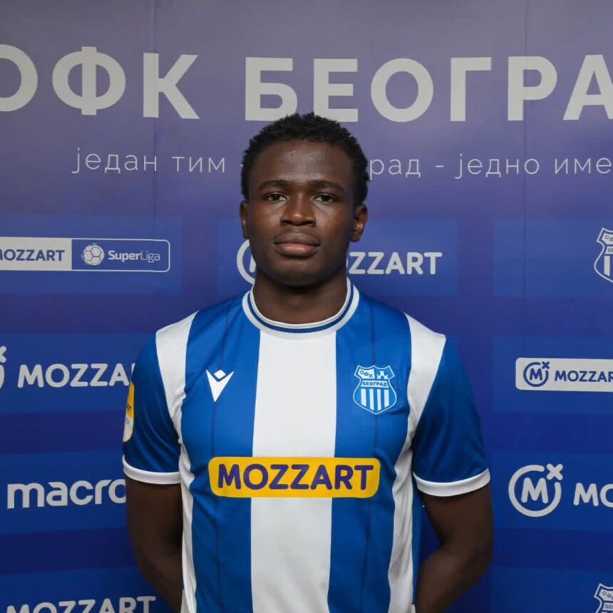 Young male soccer player in a blue and white striped jersey posing for a photo with a blue sponsor backdrop showing Mozzart logos and a team crest on his chest  trybalnews