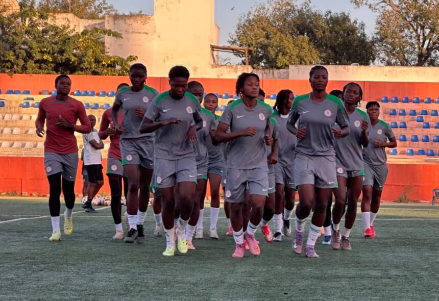 Group of female soccer players in gray uniforms jog on a field during training with orange bleachers in the background  trybalnews