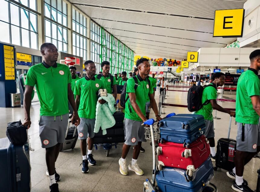 Group of men in green team uniforms walking with rolling suitcases in an airport terminal with bright yellow signage nearby  trybalnews
