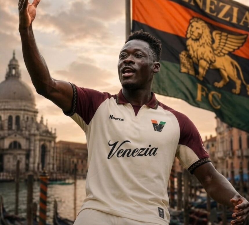 Soccer player in a Venezia FC kit raises an arm in celebration with a flag behind him in a Venetian waterfront setting  trybalnews