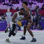 Basketball action Nigeria player in white drives with the ball as a defender in bluered guards him on a purple court arena  trybalnews