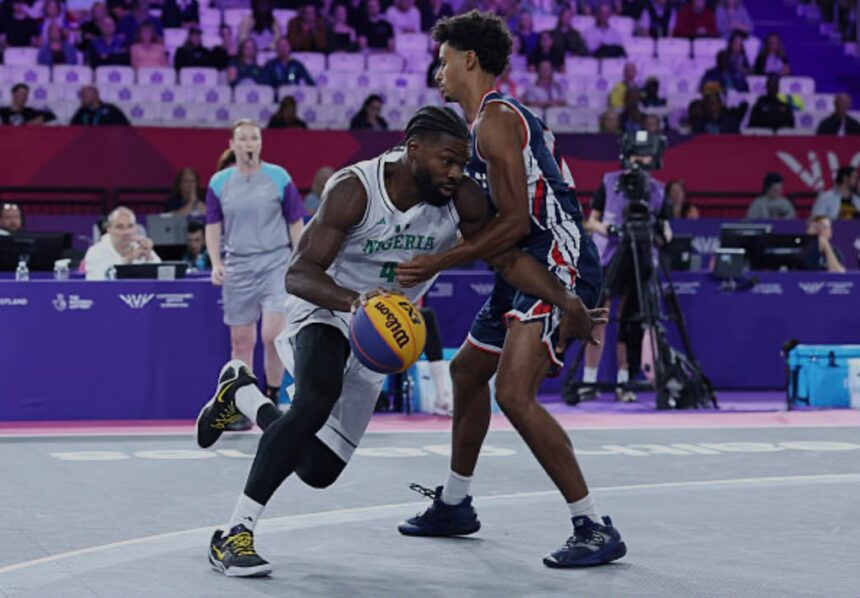 Basketball action Nigeria player in white drives with the ball as a defender in bluered guards him on a purple court arena  trybalnews