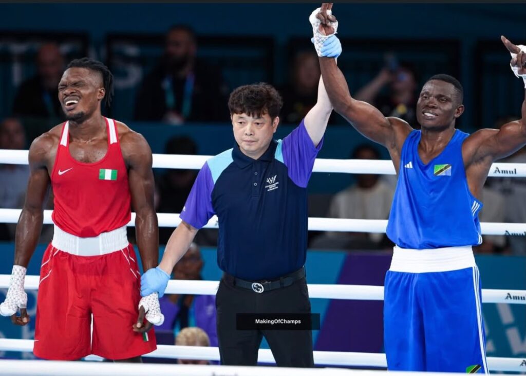 Boxers in red and blue trunks with a referee in the middle raising both fighters arms in victory inside a boxing ring  trybalnews