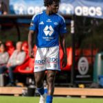 Male soccer player in blue jersey and white shorts walking on a green pitch during a game with spectators in the background  trybalnews