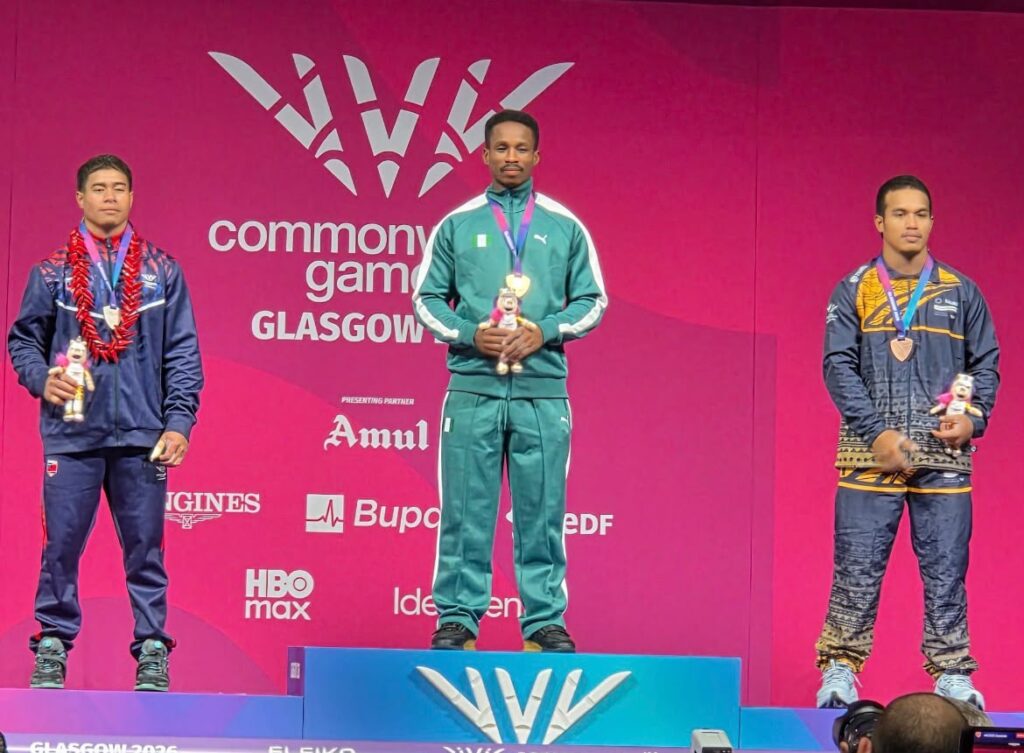 Glasgow 2026 Trybal News Three male medalists stand on a winners podium at the Commonwealth Games Glasgow center gold medalist in teal tracksuit holding his trophy trybalnews