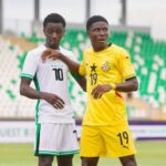 Two male soccer players on a field one in white with the number 10 and green trim the other in yellow with the number 19 standing close in a stadium  trybalnews