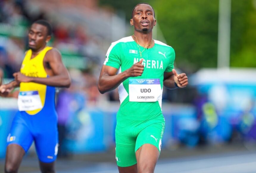 Two male sprinters race on a track foreground runner in green Nigeria kit with bib UDO LONGINES  trybalnews