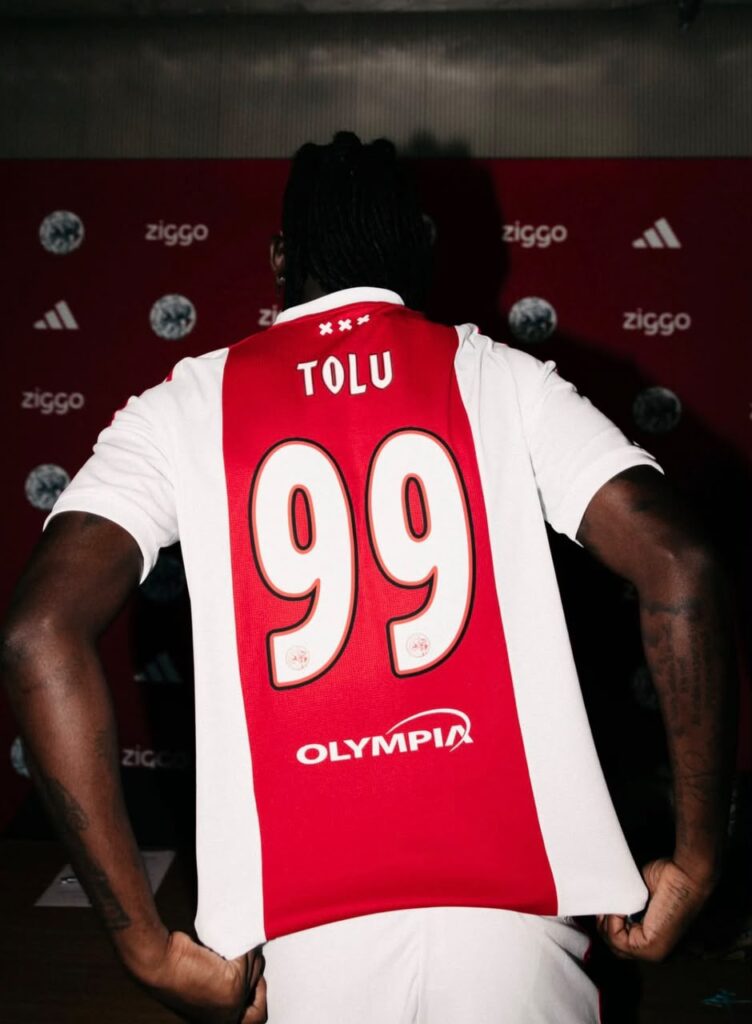 Tolu Arokodare Trybal News Back view of a player in a red and white football jersey with the name TOLU and number 99 featuring the Olympia sponsor logo trybalnews