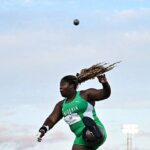 Nigerian female hammer thrower in a green uniform mid throw with the ball arcing overhead against a blue sky backdrop  trybalnews